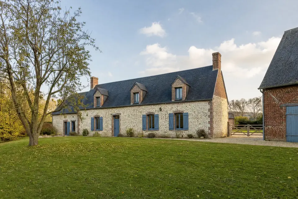 Stone farmhouse with blue shutters and a large yard